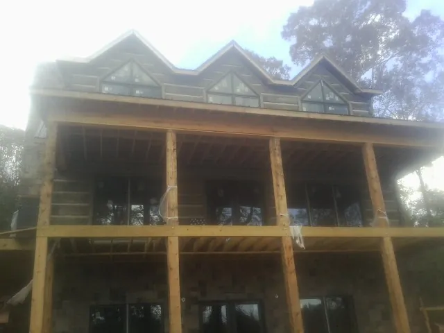 Dormers and porch framing on a large log home under construction — Roof Coating work by our crew in Homer