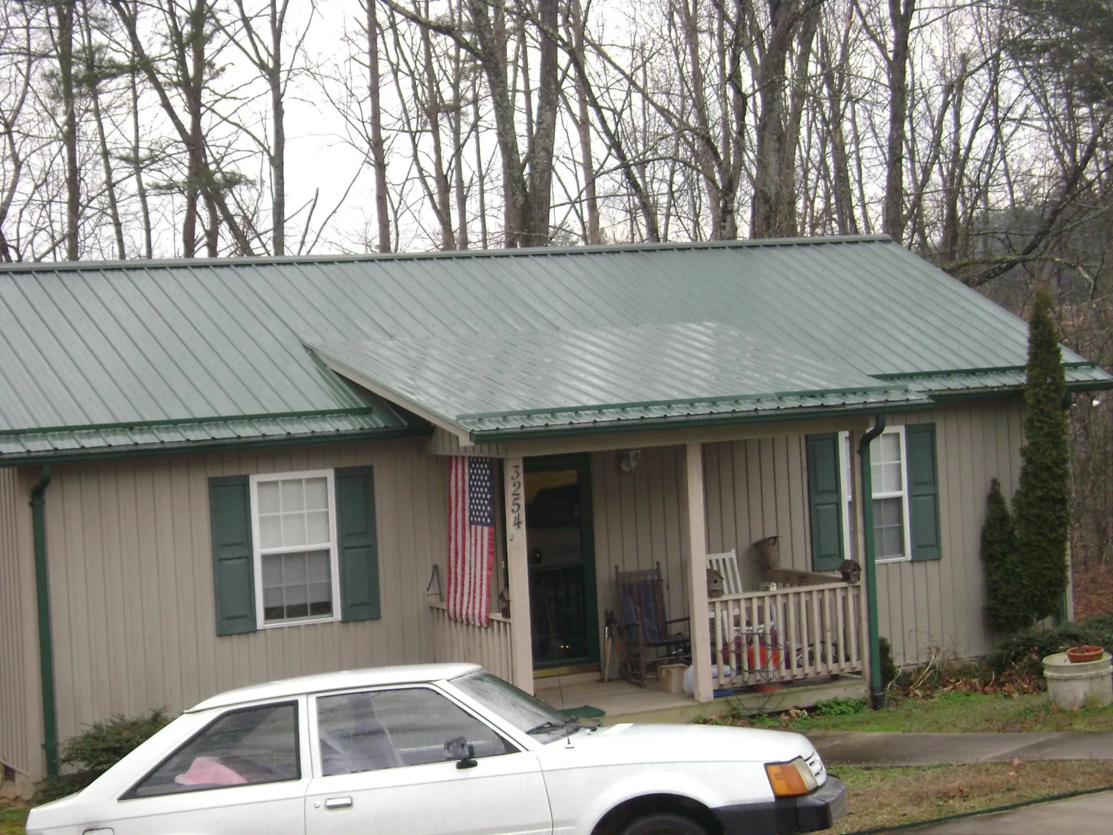 Green metal roof and front porch on a tan sided cottage in Homer