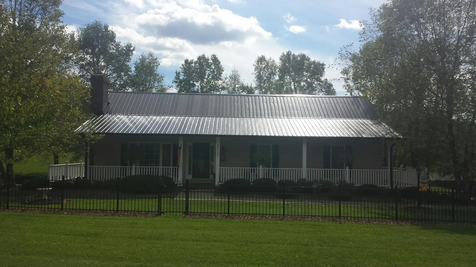 Gray metal roof on a brick ranch with a full width front porch — Gutter Guard Installation work by our crew in Homer