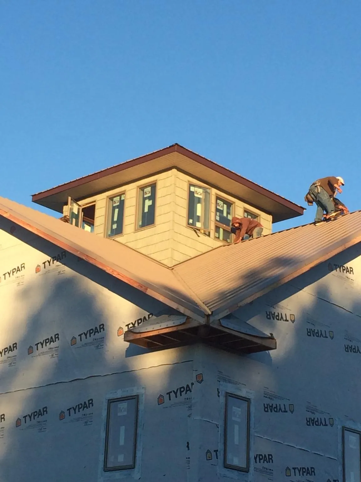 Roofers working around a rooftop cupola on a new metal roof at sunset — Roof Waterproofing in Homer by Roofing Brothers